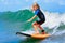 Young surfer rides on surfboard with fun on sea waves