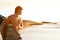 Young surfer standing by sunset