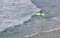 Young surfer walks into the water to confront the surf by surfing the rougher waters after a morning rain storm