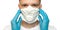 Young surgeon doctor in latex protective gloves puts on white protection mask on white background. Man in medical gloves and on