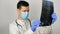 A young surgeon wearing a protective medical mask examines an X-ray of a patient's lungs and ponders the diagnosis. A