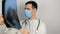 A young surgeon wearing a protective medical mask examines an X-ray of a patient's lungs and ponders the diagnosis.