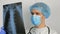 A young surgeon wearing a protective medical mask examines an X-ray of a patient's lungs and ponders the diagnosis. A