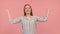 Young surprised woman with outstretched hands isolated on pink background. Unexpected guest visiting