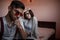 A young swarthy guy and a young brunette girl are sitting on the bed in the bedroom with sad faces. selective focus on the girl