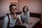 A young swarthy guy and a young brunette girl are sitting on the bed in the bedroom with sad faces. selective focus on the girl