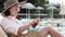 Young swarthy woman applies sunblock lotion, sunscreen moisturizer near pool during summer vacation. Closeup tanned female legs