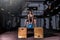 Young sweaty muscular fit girl with big muscles and strong legs doing deep squat and dip on two wooden jump boxes with heavy kettl