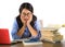 Young sweet and concentrated Asian Korean student girl in nerd glasses working cheerful on laptop computer on desk with pile of