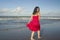 Young sweet and happy Asian Chinese woman in sarong at beautiful beach walking by the sea relaxed and blissful enjoying Summer