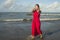 Young sweet and happy Asian Korean woman in sarong at beautiful beach walking by the sea relaxed and blissful enjoying Summer