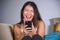 Young sweet happy and pretty Asian Chinese girl using internet social media app on mobile phone laughing cheerful having fun at ho