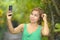 Young sweet and pretty Asian woman holding mobile phone taking selfie picture in tropical jungle smiling happy posing cool in soci