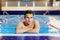 Young swimmer in the pool with goggles looking at the camera on