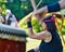 Young Taiko drummer sits on the lawn in front of her drum and beats the instrument during a performance in a public park