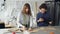 Young tailors are working with tablet, communicating and outlining clothing pattern on textile on studio desk. Light