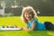 Young talented boy artist painter. Child boy draws in park laying in grass having fun on nature background. Kids