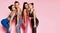 Young tall athletic women in blue, grey, brown standing behind each other. Fitness girls posing on pink background.