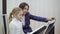 Young teacher with little cute girl playing on the electric piano.