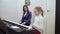 Young teacher with little cute girl playing on the electric piano.