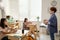 Young teacher standing in front of intercultural schoolgirls at lesson