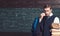 Young teacher taking off his glasses. Intelligent man in suit holding heap of books