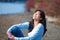 Young teen girl in blue shirt and jeans laughing along rocky lake shore