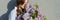 Young teen girl with bouquet of lilac near gray wall outdoor background, panoramic banner, girl in profile, copy space