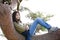 Young teen girl relaxing on tree limb