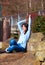 Young teen girl sitting on large boulders or rocks outdoors, arms raised over head, excited and happy