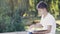 Young teenage boy in park sitting on the curb and writing their homework.