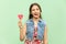 Young teenage girl with blondie long hair, wink at camera, tongue out, holds lolipop, having funny look.