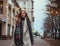 Young teenage girl in coat and long scarf on street of european city, elegant style of fashionable clothes