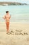 Young teenage girl with I love ocean message on sand