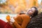 a young teenage girl posing in an autumn forest, lying on a tree, by the riverbank, enjoying the beautiful nature and bright