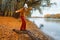 a young teenage girl posing in the autumn forest, standing on a fallen tree on the riverbank, beautiful nature and bright yellow