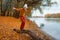 a young teenage girl posing in the autumn forest, standing on a fallen tree on the riverbank, beautiful nature and bright yellow