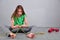 Young teenage girl sitting on the floor with skipping rope and dumbbells relaxing having rest in studio.