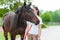 Young teenage girl tenderly kissing her favorite chestnut horse