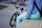 Young teenage girls with a phone sitting next to a bicycle.