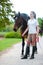 Young teenage lady leads her favorite bay horse after training