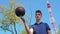 A young teenage man spins the ball on his finger while on the basketball court.