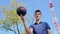 A young teenage man spins the ball on his finger while on the basketball court.