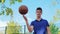 A young teenage man spins the ball on his finger while on the basketball court.