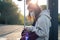 A young teenage woman is waiting for a bus at a bus stop early in the morning.