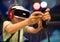 Young teenager boy using a Virtual reality headset with goggles and hands motion controllers in playing game zone. Modern