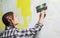 Young teenager brunette girl with long hair applying white putty on a wall and smearing by putty knife in a room of renovating hou