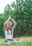 Young teenager brunette girl with long hair practicing yoga on the grass in park