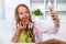 Young teenager girl eating pizza in the kitchen - making a selfie