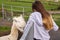 Young teenager girl feeding funny lama in an open farm or zoo. Warm summer sunny day. Learning nature concept